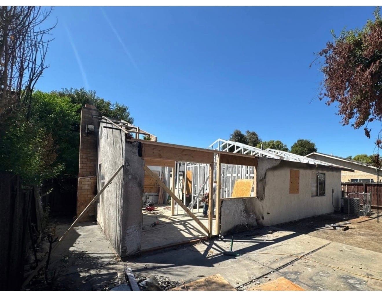 A fire-damaged single-family house mid-reframing, with new roof trusses set